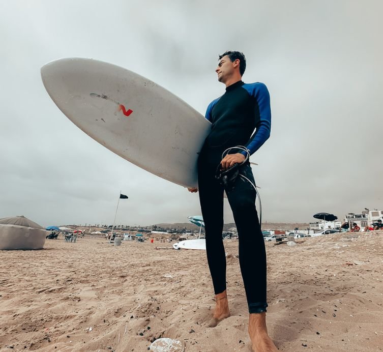 surfer standing in taghazout beach holding a board
